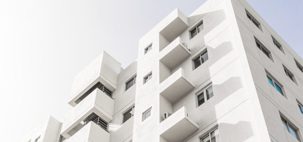 Low angle shot of a facade of a white modern building under a blue clear sky A low angle shot of a facade of a white modern building under a blue clear sky