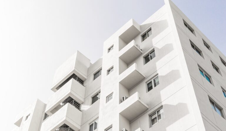 A low angle shot of a facade of a white modern building under a blue clear sky