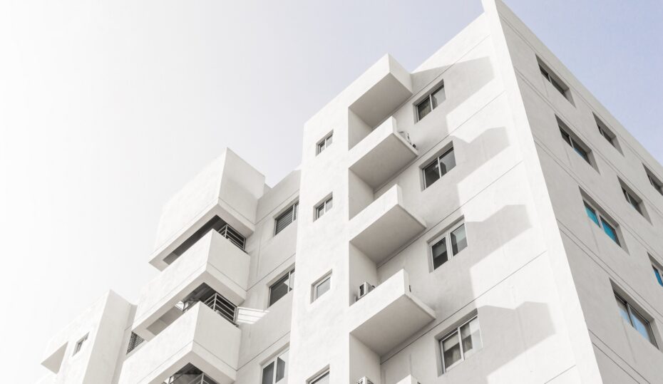 A low angle shot of a facade of a white modern building under a blue clear sky