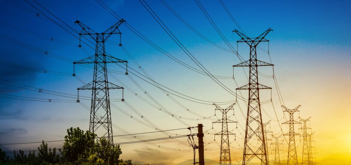 Sun setting behind the silhouette of electricity pylons Sun setting behind the silhouette of electricity pylons