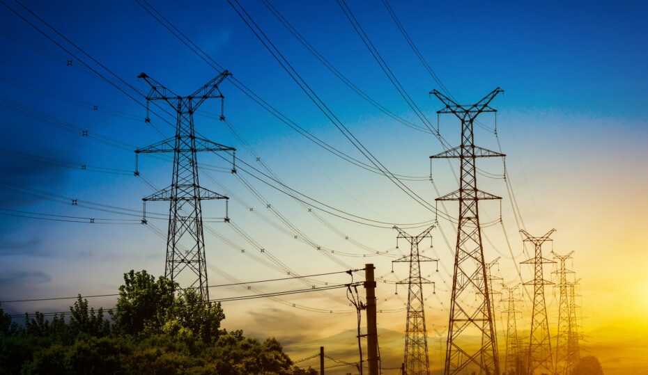 Sun setting behind the silhouette of electricity pylons